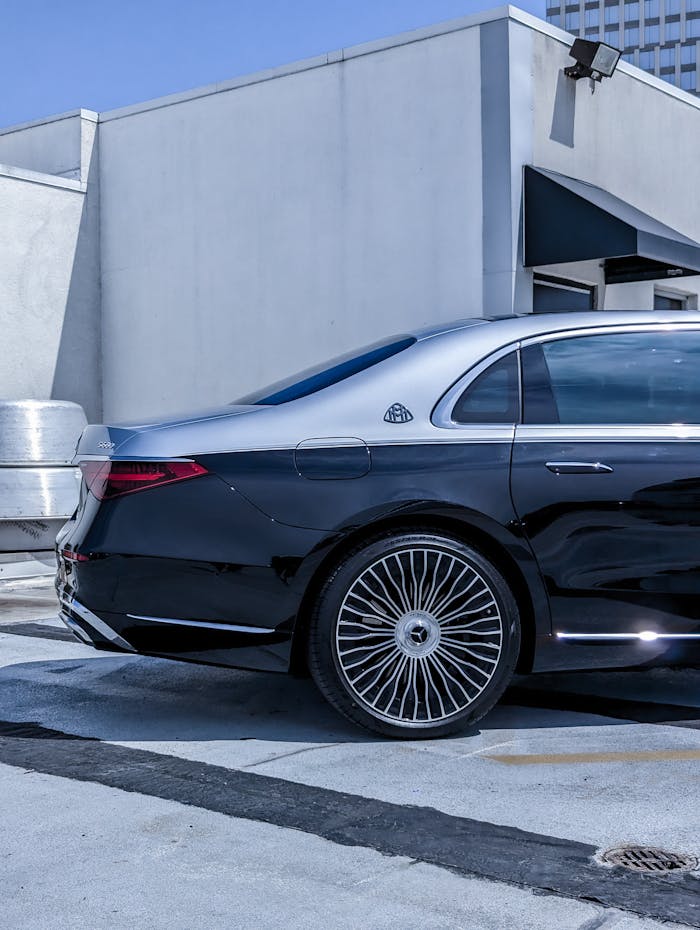 Sleek rear view of a luxury black car parked on an urban rooftop with striking alloy wheels.